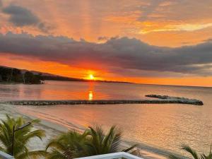 a sunset over the water with a beach at serendipity on the beach Ocho Rios in Saint Annʼs Bay