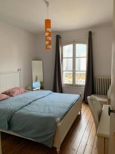 um quarto com uma cama, uma cadeira e uma janela em Maison Serpolette - maison entiere em Trouville-sur-Mer