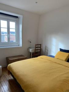 um quarto com uma cama amarela e uma janela em Maison Serpolette - maison entiere em Trouville-sur-Mer