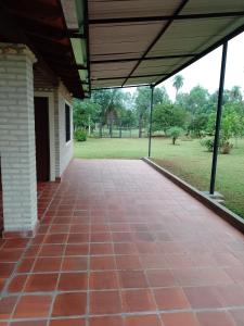 een open veranda met een bakstenen vloer en een dak bij La herencia in Caacupé