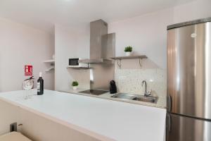 a white kitchen with a sink and a refrigerator at Roisa Centro in Madrid +150 photos