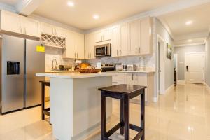 a kitchen with white cabinets and a black stool at serendipity on the beach Ocho Rios in Saint Annʼs Bay