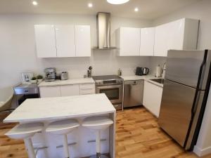 una cocina con armarios blancos y electrodomésticos de acero inoxidable en 3 bedroom near Olympic Stadium en Montreal