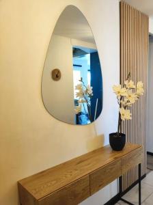 een kamer met een spiegel en een houten tafel met een plant bij Appart proche plage Calais in Calais