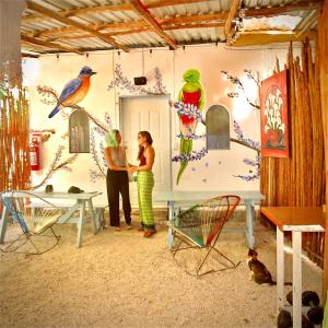 zwei Frauen stehen vor einer Wand mit Vögeln darauf in der Unterkunft Hostalito Lahar in Bacalar