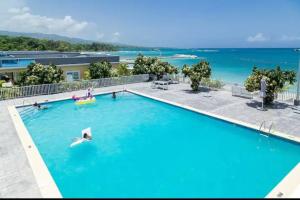 a woman swimming in a pool with the ocean in the background at serendipity on the beach Ocho Rios in Saint Annʼs Bay