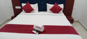 un letto con cuscini rossi e bianchi e due telecomandi di RK GRAND LUXURY AC ROOMS a Guntur