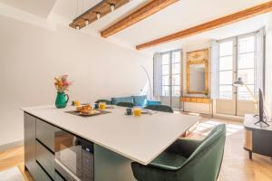 Il dispose d'une cuisine et d'un salon avec une grande table et des chaises blanches. dans l'établissement Magnifique appartement centre historique, à Aix-en-Provence