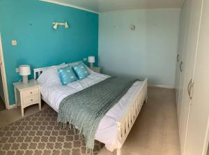 a bedroom with a large bed with blue walls at Seaview Bungalow, Thurlestone, Beaches Nearby in Thurlestone