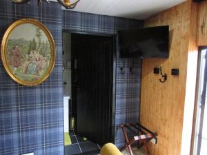 a room with a tv and a blue tiled wall at Woodston Fishing Station in Saint Cyrus