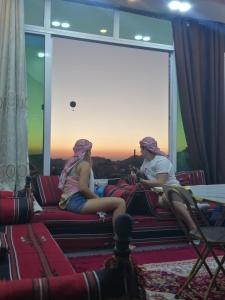Duas raparigas sentadas num sofá a ver o pôr-do-sol. em Petra paradise home em Wadi Musa