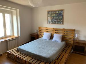um quarto com uma cama de madeira e 2 almofadas em Maison de ville au cœur d'un village de caractère dans le jura em Saint-Julien