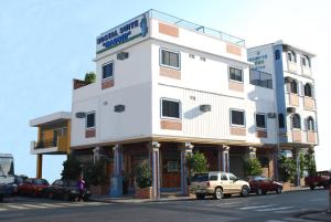 un edificio blanco con coches estacionados frente a él en Hostal Suites Madrid, en Guayaquil