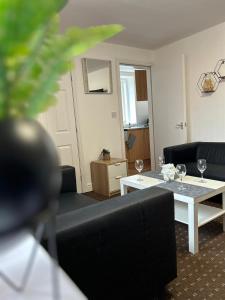 uma sala de estar com sofás e uma mesa com copos de vinho em Bv Cozy Deighton Studio with Free Parking - Budget-Friendly Stay em Huddersfield