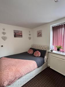 um quarto com uma cama com um cobertor rosa e uma janela em Bv Cozy Deighton Studio with Free Parking - Budget-Friendly Stay em Huddersfield