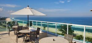 a balcony with tables and chairs and the ocean at Atlantico Sul Hotel in Rio de Janeiro