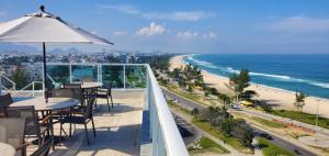 a balcony with tables and an umbrella and a beach at Atlantico Sul Hotel in Rio de Janeiro