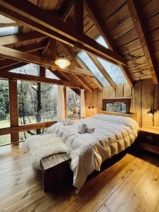 ein großes Bett in einem Zimmer mit einem großen Fenster in der Unterkunft Hogar de Montaña in Villa La Angostura