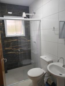 La salle de bains est pourvue de toilettes, d'une douche et d'un lavabo. dans l'établissement Canto Verde Aptos I, à Caraguatatuba