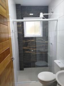 La salle de bains est pourvue de toilettes, d'une douche et d'une fenêtre. dans l'établissement Canto Verde Aptos I, à Caraguatatuba