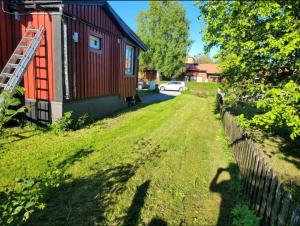 a yard next to a red house with a fence at Remarkable 1-Bed Apartment in Orebro in Örebro