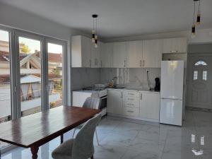 a kitchen with a wooden table and a refrigerator at Jordanovi Premium Apartment in Kavadarci