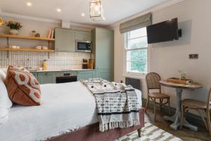 a bedroom with a bed and a table and a kitchen at The Cotham Arms Apartments in Bristol