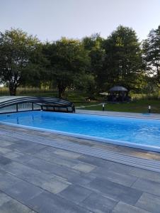 uma grande piscina azul com um gazebo em Luksusowe domki Mazury em Mrągowo