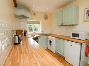 a kitchen with green cabinets and a washer and dryer at The Coach House in Ludlow