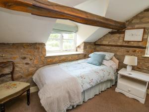 a bedroom with a bed and a stone wall at The Coach House in Ludlow