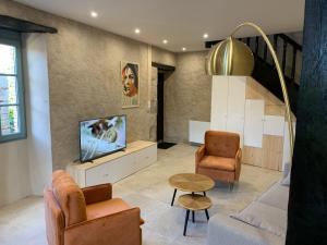 - un salon avec une télévision, un canapé et des chaises dans l'établissement La Maison des Ecureuils - Bruniquel, à Bruniquel