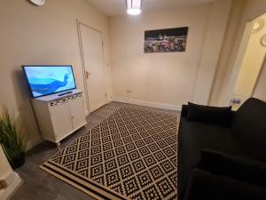 One Bedroom Apartment with Garden في لندن: غرفة معيشة مع أريكة وتلفزيون بشاشة مسطحة