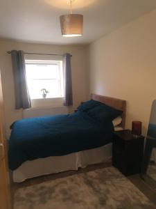 1 dormitorio con 1 cama con edredón azul y ventana en One Bedroom Apartment with Garden, en Londres