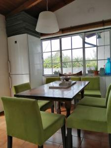cocina con mesa de madera y sillas verdes en A Casa da Bicicleta, en Lousã