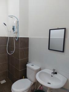 La salle de bains est pourvue de toilettes, d'un lavabo et d'un miroir. dans l'établissement HM HOMESTAY TAWAU, à Kampong Parit