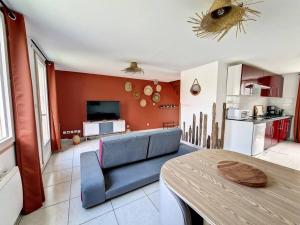 a living room with a blue couch and a kitchen at Le Terracotta, Proche plage in Oye-Plage