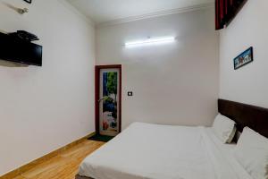 a white bedroom with a bed and a door at OYO Xpress Home in Lucknow