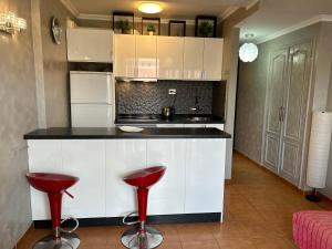 a kitchen with white cabinets and red stools at 5 min walk to Gold Mile and 7min to best Las Americas Beach WiFi in Arona