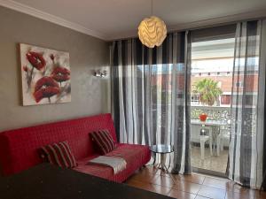 a living room with a red couch in front of a window at 5 min walk to Gold Mile and 7min to best Las Americas Beach WiFi in Arona