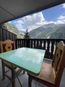 a table and chairs on a balcony with a view of mountains at Superbe studio au pied des oeufs in Champagny-en-Vanoise
