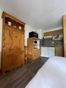 a bedroom with a large bed and a kitchen at Superbe studio au pied des oeufs in Champagny-en-Vanoise