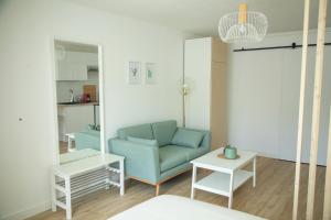 een woonkamer met een blauwe bank en een tafel bij Le Jade - Appart'Escale in Saint-Nazaire