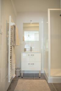 ein weißes Badezimmer mit einem Waschbecken und einem Spiegel in der Unterkunft Le Jade - Appart'Escale in Saint-Nazaire