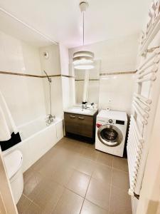 een badkamer met een wasmachine en een wastafel bij Parc des Expositions Appartement 4 personnes Parking Gratuit in Villepinte