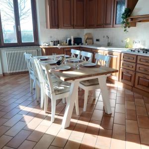 - une cuisine avec une table en bois et des chaises blanches dans l'établissement B&B La casa in campagna, à Fidenza