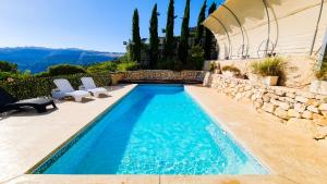 a swimming pool with two white chairs and a house at עיינות ספיר - Einot Sapir in Sappir