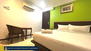 a bedroom with a bed and a table and a green wall at Hotel Grand Palace Ampang in Ampang