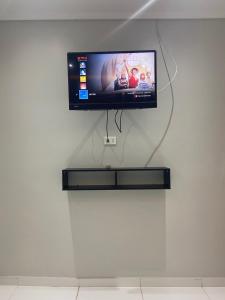 Elle comprend une télévision à écran plat suspendue sur un mur blanc. dans l'établissement Apartamento Espanha, à Ciudad del Este