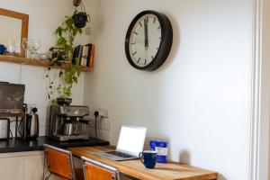 a clock hanging on a wall above a table with a laptop at Unique private apartment w/ Easy access to Central London in London