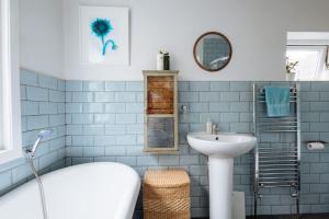 Łazienka wyłożona jest niebieskimi kafelkami i wyposażona w wannę oraz umywalkę. w obiekcie Unique private apartment w/ Easy access to Central London w Londynie
